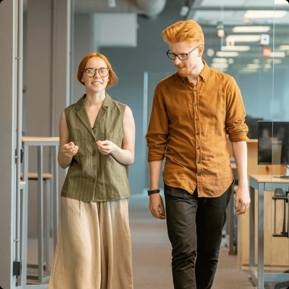 Two colleagues walk down a corridor in deep discussion