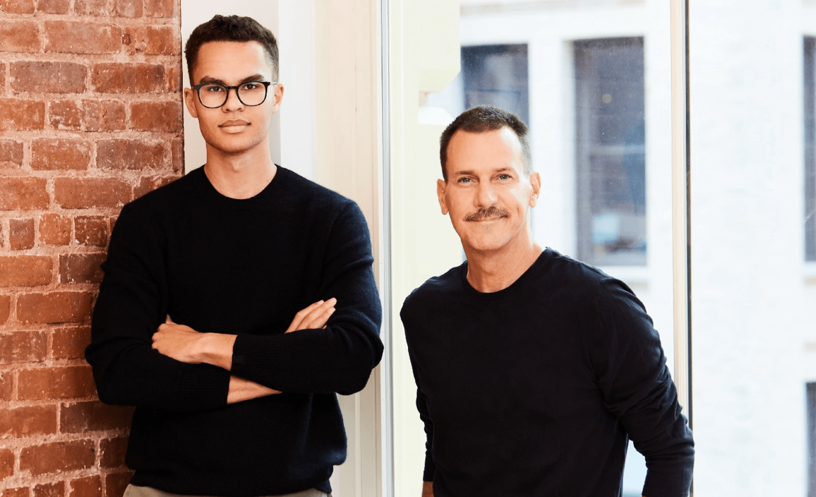 2 men standing against a wall